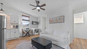 A modern kitchen with white cabinets, a microwave, and a dining area with a table and chairs. - Luxe Living Suites #3, 3 minutes to DT Cincy (Covington)