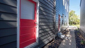 A residential building with a red garage door and a white window shutter. - Luxe Living Suites #3, 3 minutes to DT Cincy (Covington)