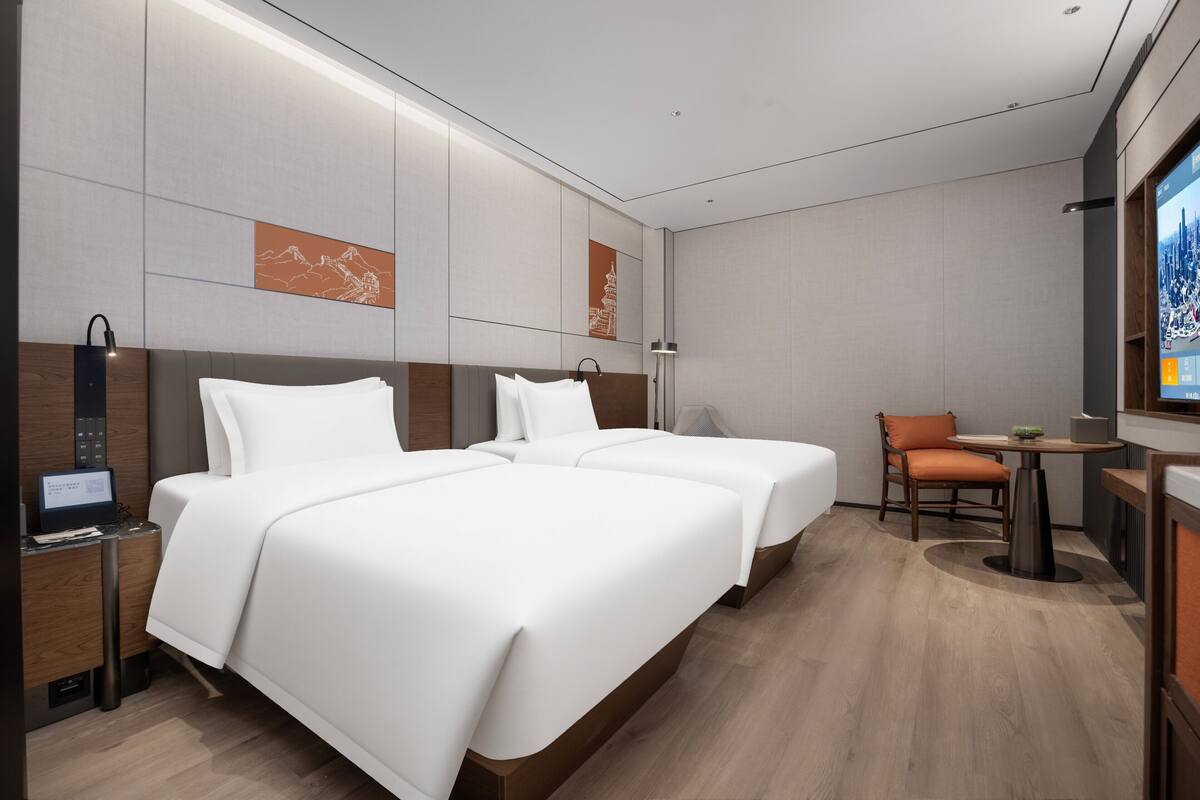 Une chambre d’hôtel moderne avec deux lits, un bureau et une chaise.
