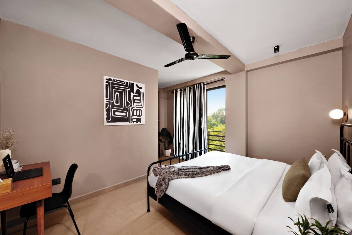 Un dormitorio moderno con una cama, un escritorio y un ventilador de techo.