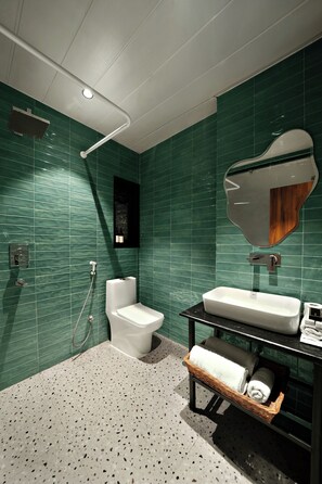 Une salle de bain moderne avec des murs recouverts de carreaux verts, des toilettes blanches, un lavabo avec un miroir et un porte-serviettes.
