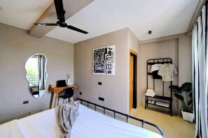 Un dormitorio con cama, escritorio, espejo, armario y ventilador de techo.