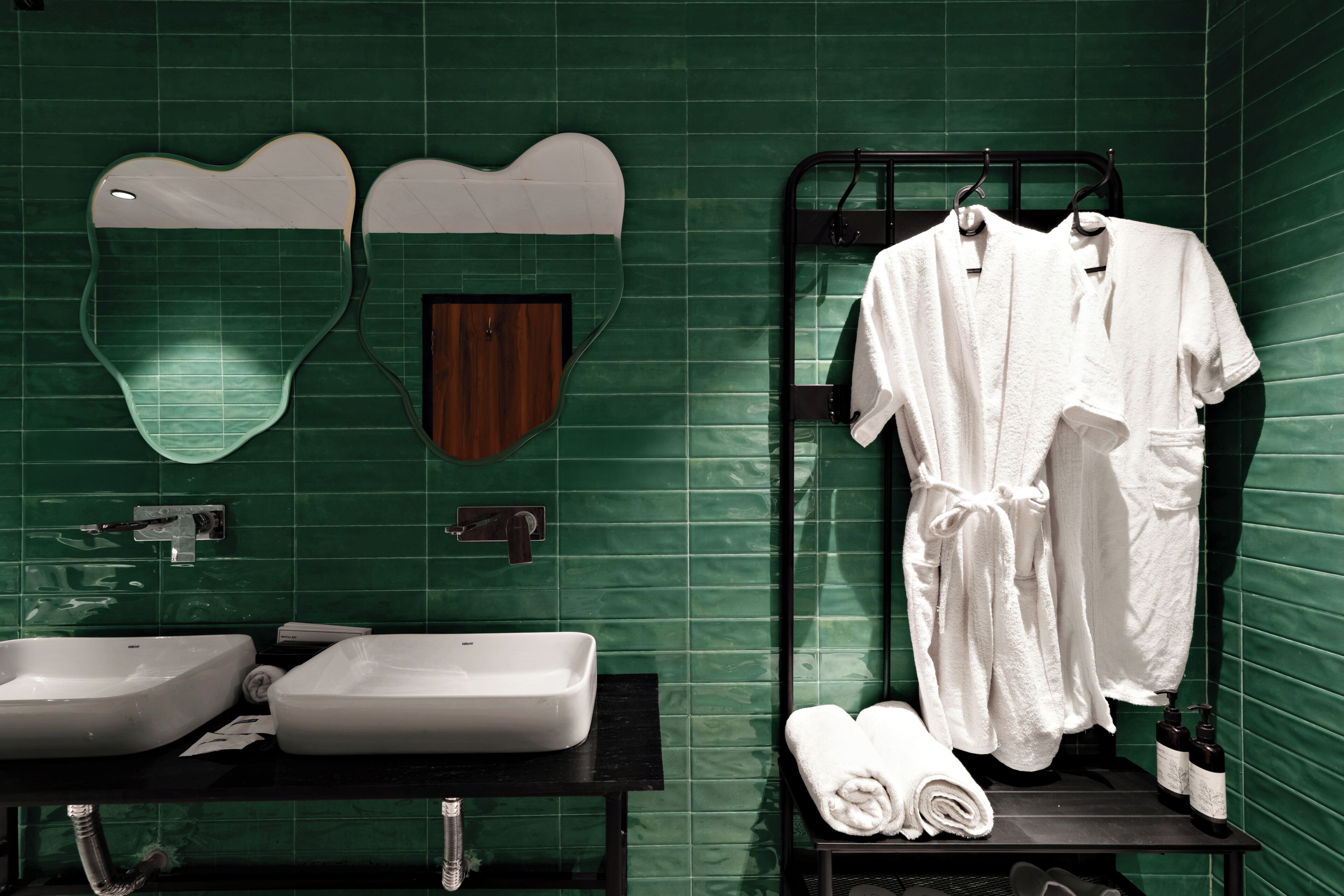 Une salle de bain avec deux lavabos, un miroir, un porte-serviettes et une porte en bois.