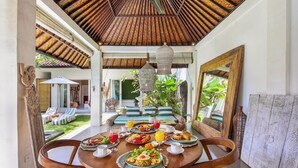 Un coin repas avec une table ronde mise pour le petit-déjeuner, entourée de chaises en osier.