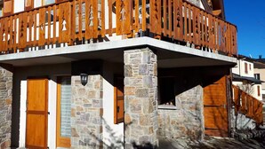 Un edificio in pietra con un balcone in legno e un'uscita.