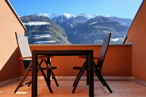 Un balcon avec une table et des chaises, d’où l’on peut admirer la vue sur les montagnes enneigées.