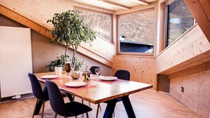 A dining area with a wooden table, chairs, and a potted plant. - Apartment Luam - Alpstay (Naturno)