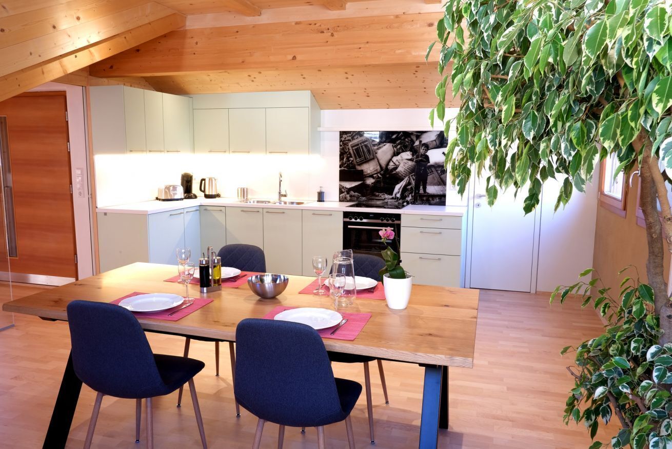 Une cuisine moderne avec des meubles blancs, une table à manger en bois et des chaises bleues.
