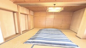 A room with tatami flooring, a bed with a striped blanket, wooden cabinets, and a ceiling light fixture. - 7-minute walk from JR Kuroiso Station｜Free high-speed Wi-Fi｜Private floor (Chuocho, Nasushiobara-shi)