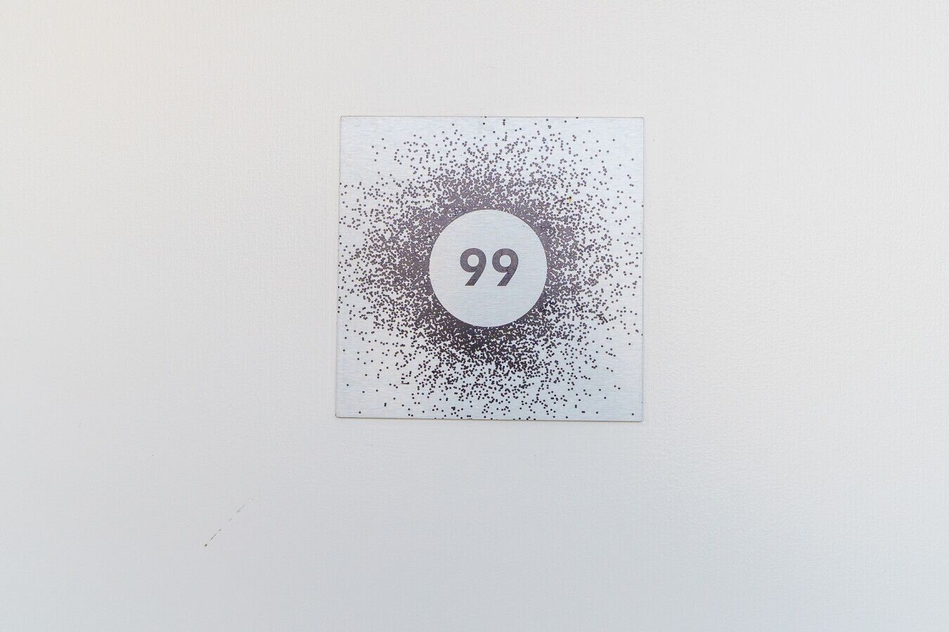 A square sign with the number 99 in the center, surrounded by a pattern of dots.