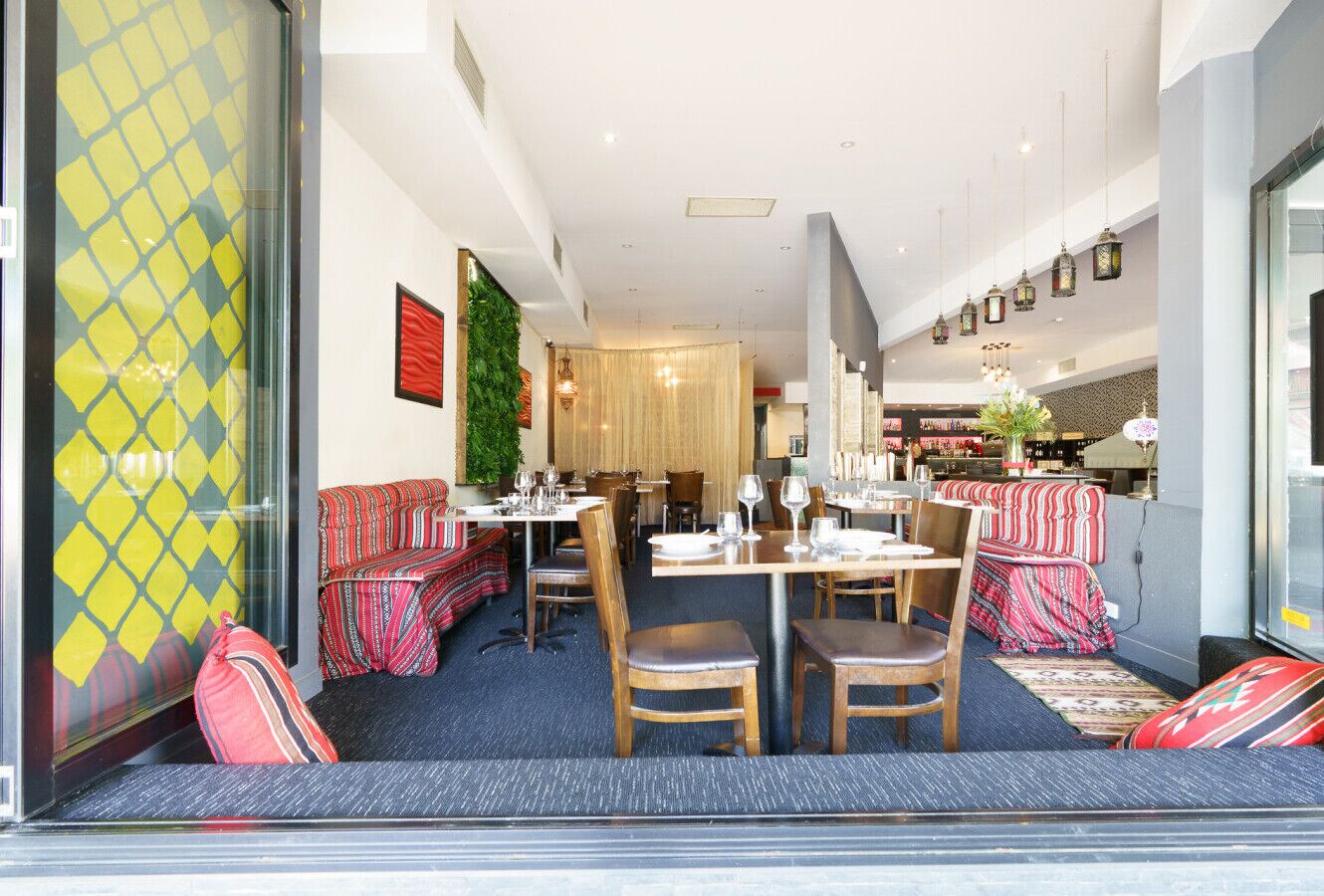 Un ristorante con sala centrale, posti a sedere tipo bancone e un bar.