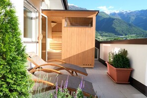 A balcony with wooden furniture, a potted plant, and a view of mountains. - Apartment Plantitsch - Alpstay (Naturns)