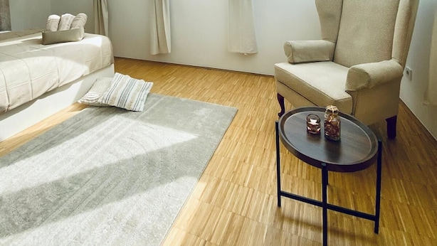Ett modernt sovrum i loftstil med ett stort takfönster, en bekväm fåtölj, ett litet bord och en mysig matta.