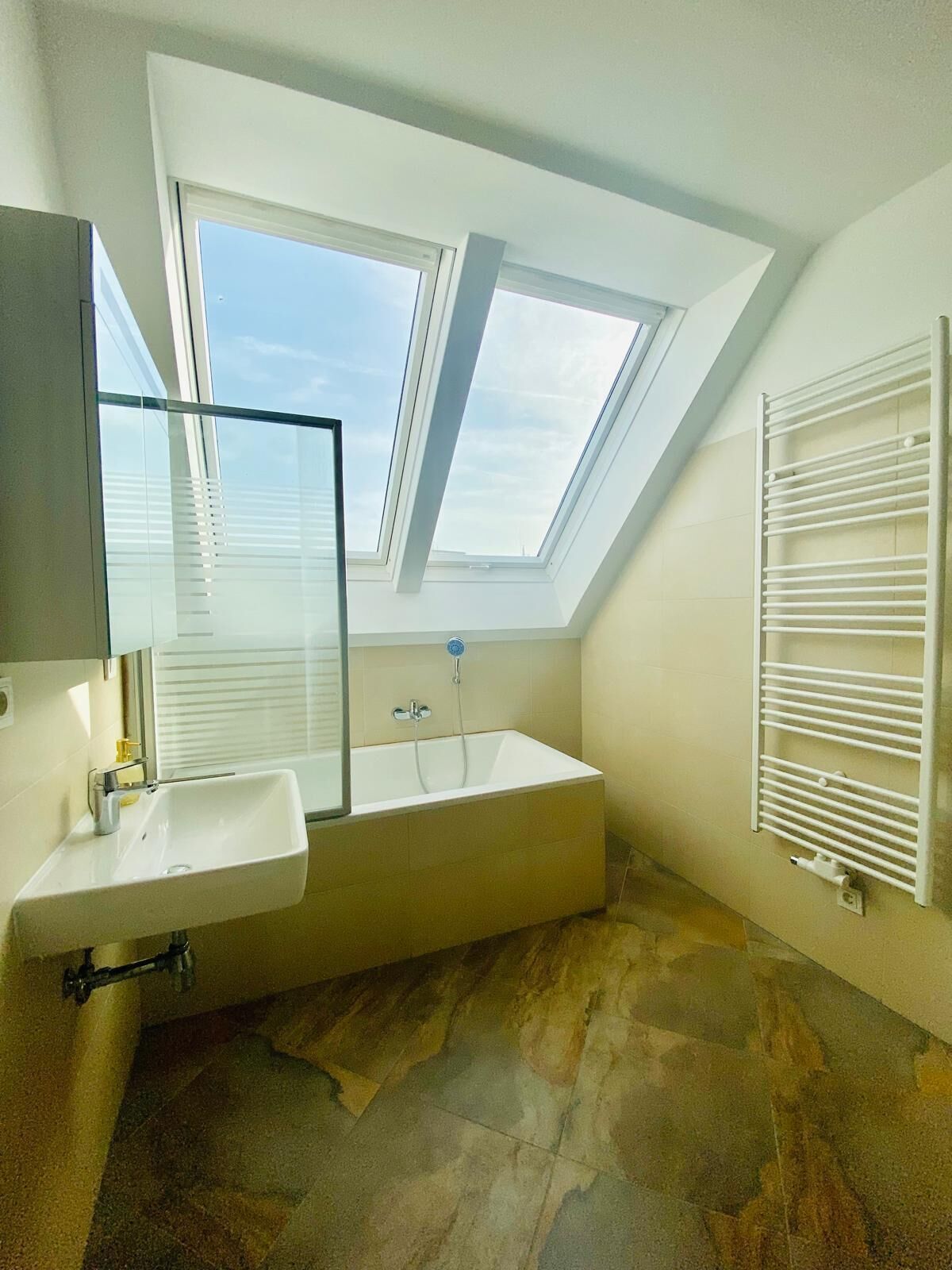 A modern bathroom with a skylight, a freestanding bathtub, and a built-in sink.