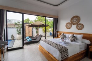 Un dormitorio moderno con una cama grande, vistas al jardín a través de puertas de vidrio y un pequeño rincón de descanso con una silla y una sombrilla.
