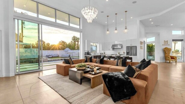 A spacious living room with a large sofa, coffee table, and a chandelier. - Miracle Retreat (Palm Springs)