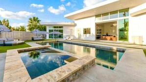 A modern house with a swimming pool, outdoor seating, and a large glass door entrance. - Miracle Retreat (Palm Springs)