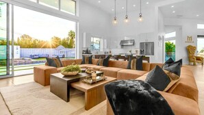 A spacious living room with a large sofa, a coffee table, and a view of the outdoors. - Miracle Retreat (Palm Springs)