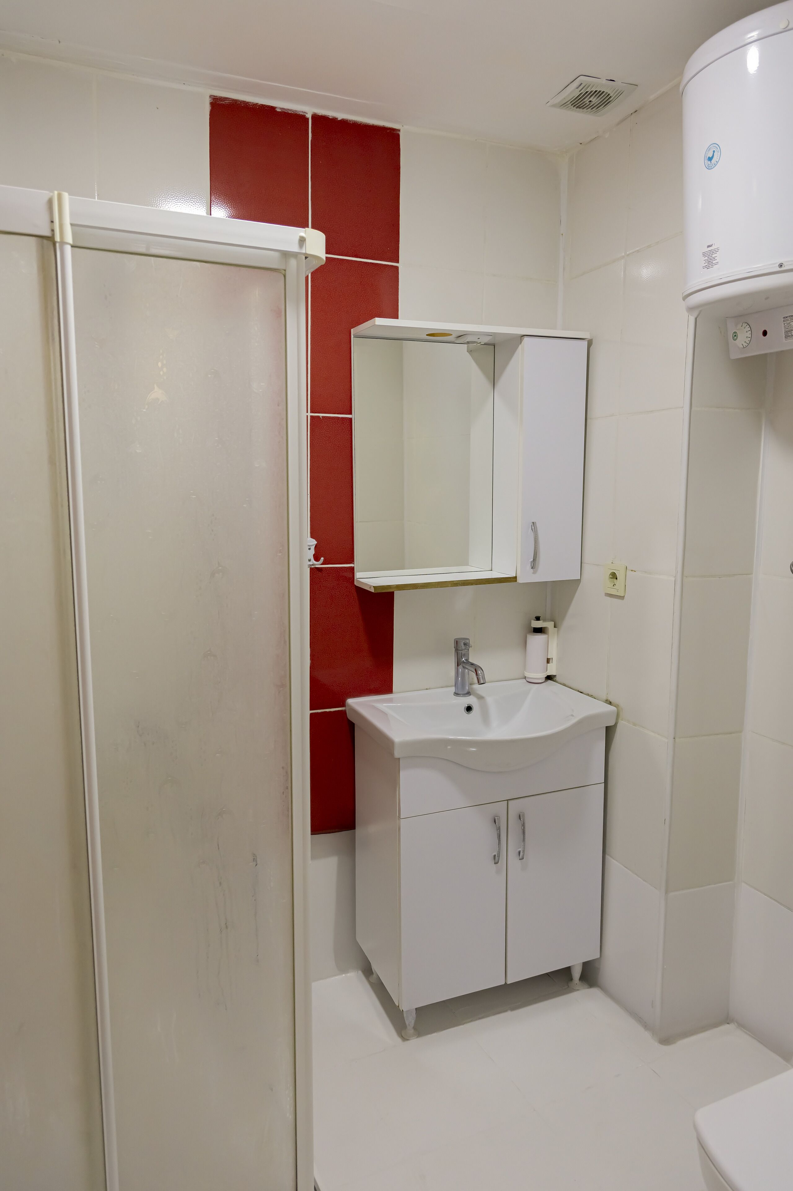 Ein Badezimmer mit Waschbecken, Spiegel und einer roten Akzentwand.