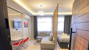 A modern hotel room with a sofa, a dining area with chairs, a bed, and a large window with curtains. - VEFA HISTORICAL SUITES HOTEL (İstanbul)