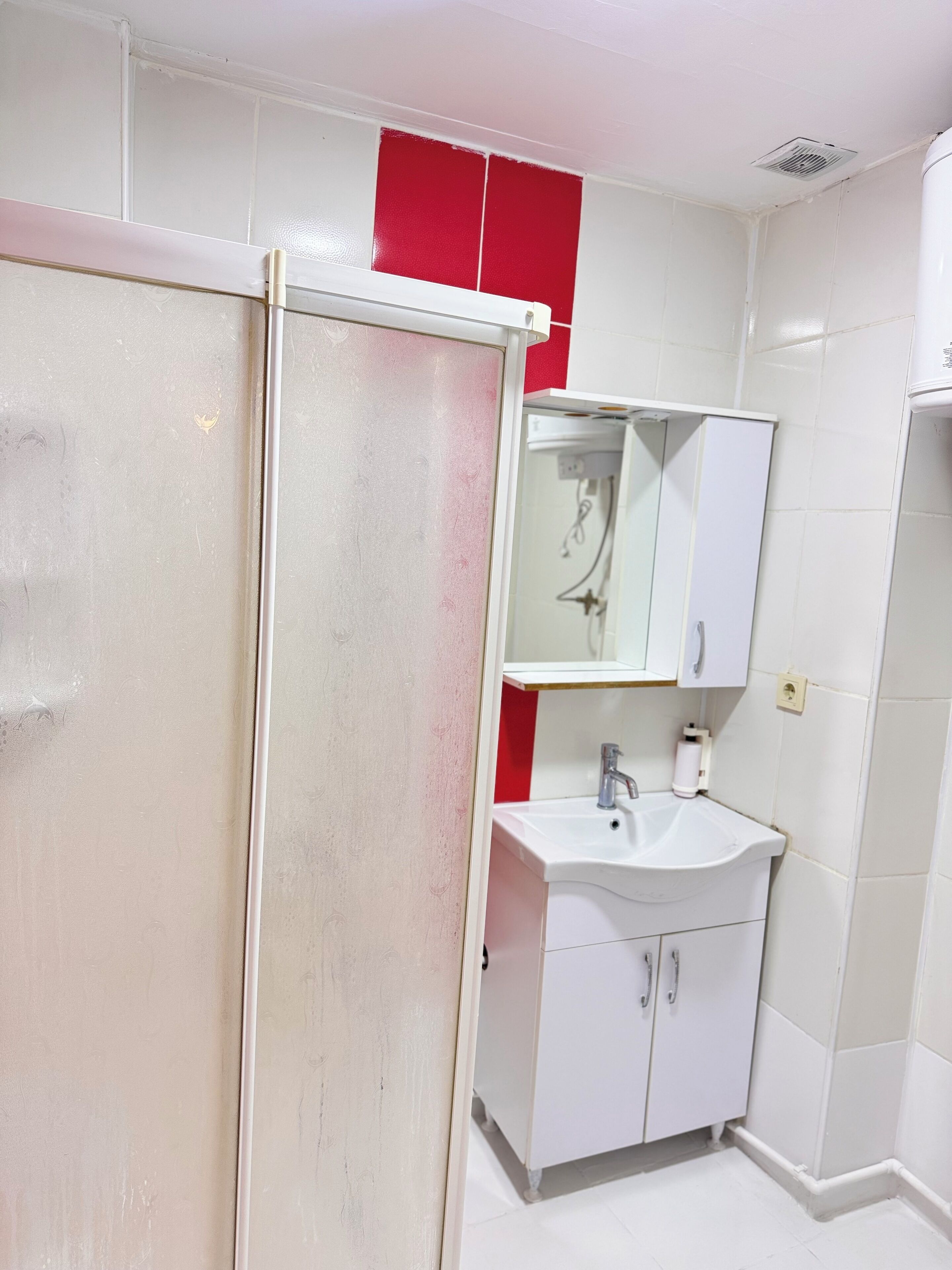 Une salle de bain avec un lavabo blanc, un miroir et un meuble.