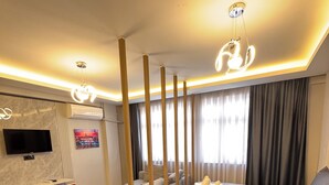 A modern bedroom with a large bed, a TV, a desk with chairs, and a large window with curtains. - VEFA HISTORICAL SUITES HOTEL (İstanbul)