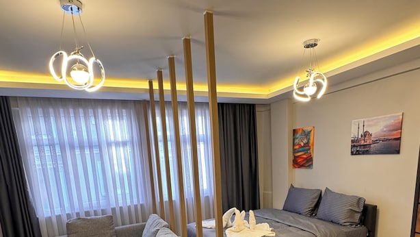 A modern bedroom with a bed, a sofa, a coffee table, and a large window with curtains. - VEFA HISTORICAL SUITES HOTEL (İstanbul)