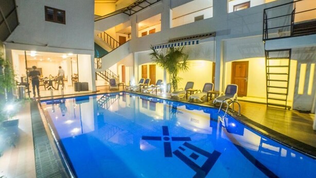 A swimming pool with lounge chairs and a staircase leading to upper floors. - Seaport Negombo (Negombo)