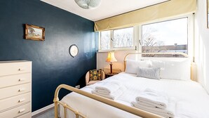 Camera da letto con un letto, una cassettiera, una sedia, una lampada e una finestra vista edifici.