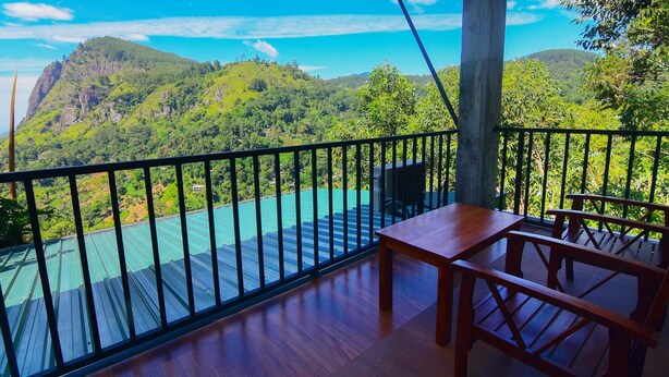 A balcony with a view of a mountainous landscape and a turquoise body of water.