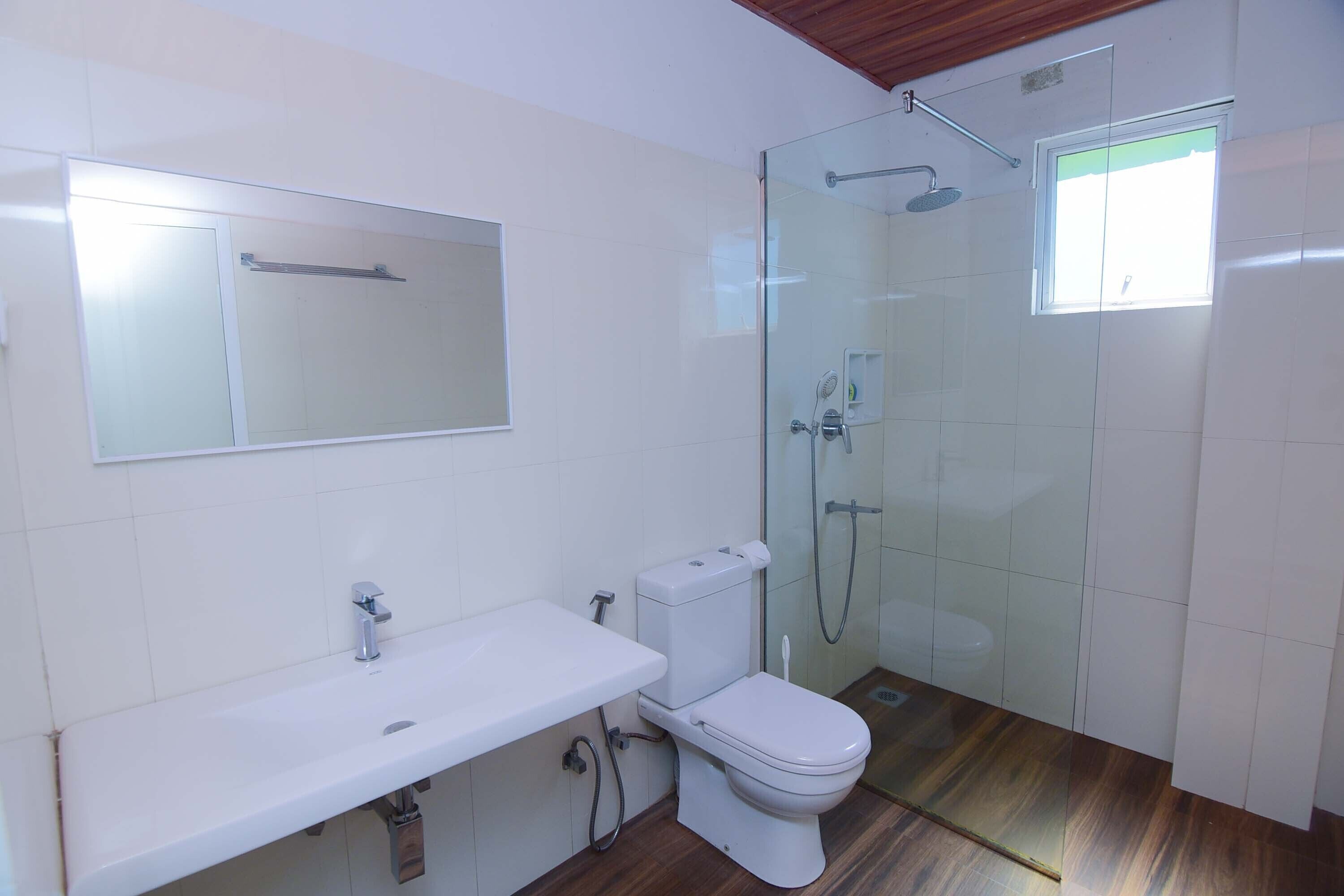 A bathroom with a white sink, toilet, and glass-enclosed shower.