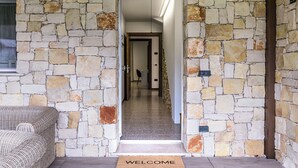 Corredor de paredes de pedra que leva a um quarto com um sofá de vime.