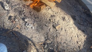 Tuli palaa betonipinnalla, ja taustalla näkyy puukaso sekä metallirakenne.