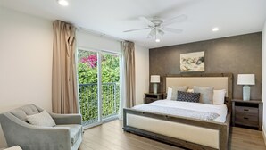 Ein Schlafzimmer mit einem großen Bett, zwei Nachttischen, einem Sessel und einem Deckenventilator.