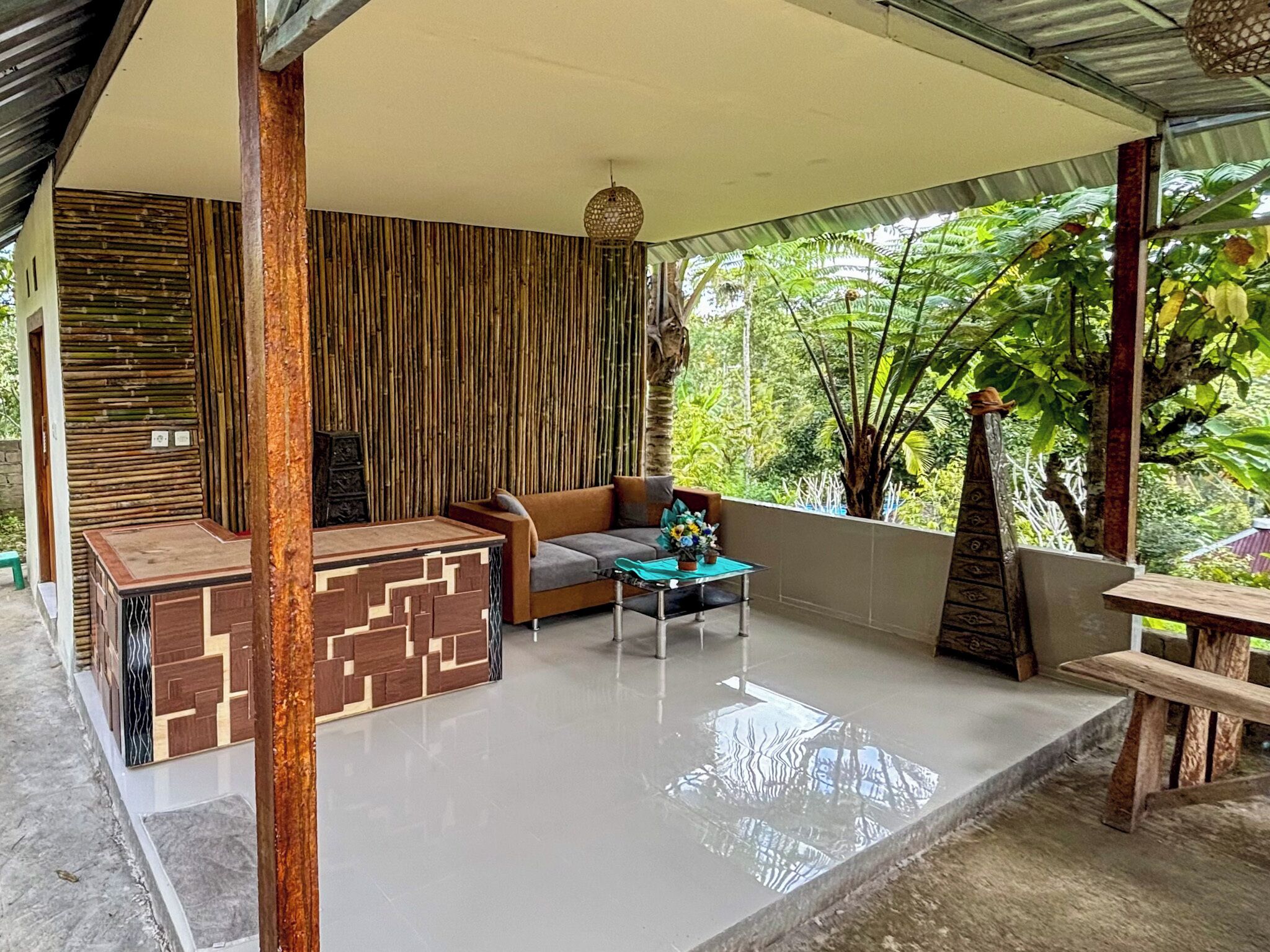 A covered outdoor seating area with a sofa, a table, and a decorative wooden structure.