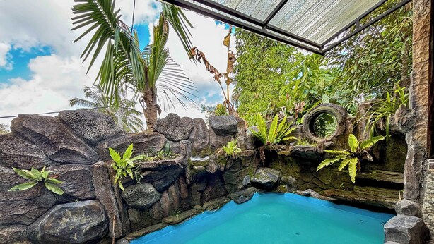 A pool surrounded by natural rock formations and tropical plants, with a clear blue sky in the background. - Pondok Sulangai Villas by AGATA (Sulangai)