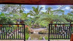 A wooden deck with a view of a tropical garden, including a pond and various plants. - Pondok Sulangai Villas by AGATA (Sulangai)