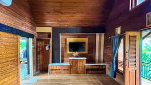 A wooden cabin interior with a wooden bench, a small table with a vase, and a mounted television. - Pondok Sulangai Villas by AGATA (Sulangai)