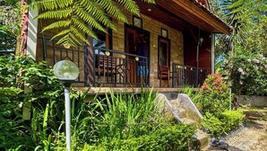 A wooden house with a porch, surrounded by lush greenery and a clear blue sky. - Pondok Sulangai Villas by AGATA (Sulangai)