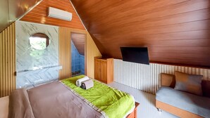 A bedroom with a bed, a sofa, a mirror, and a built-in TV. - Pondok Sulangai Villas by AGATA (Sulangai)