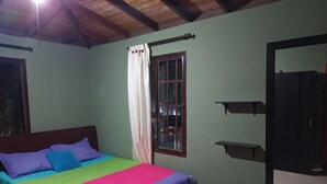 Une chambre à coucher avec un lit, une fenêtre avec des rideaux, un miroir et une étagère.
