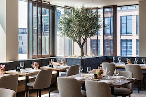 Un restaurante con varias mesas, sillas y un gran árbol en el centro.