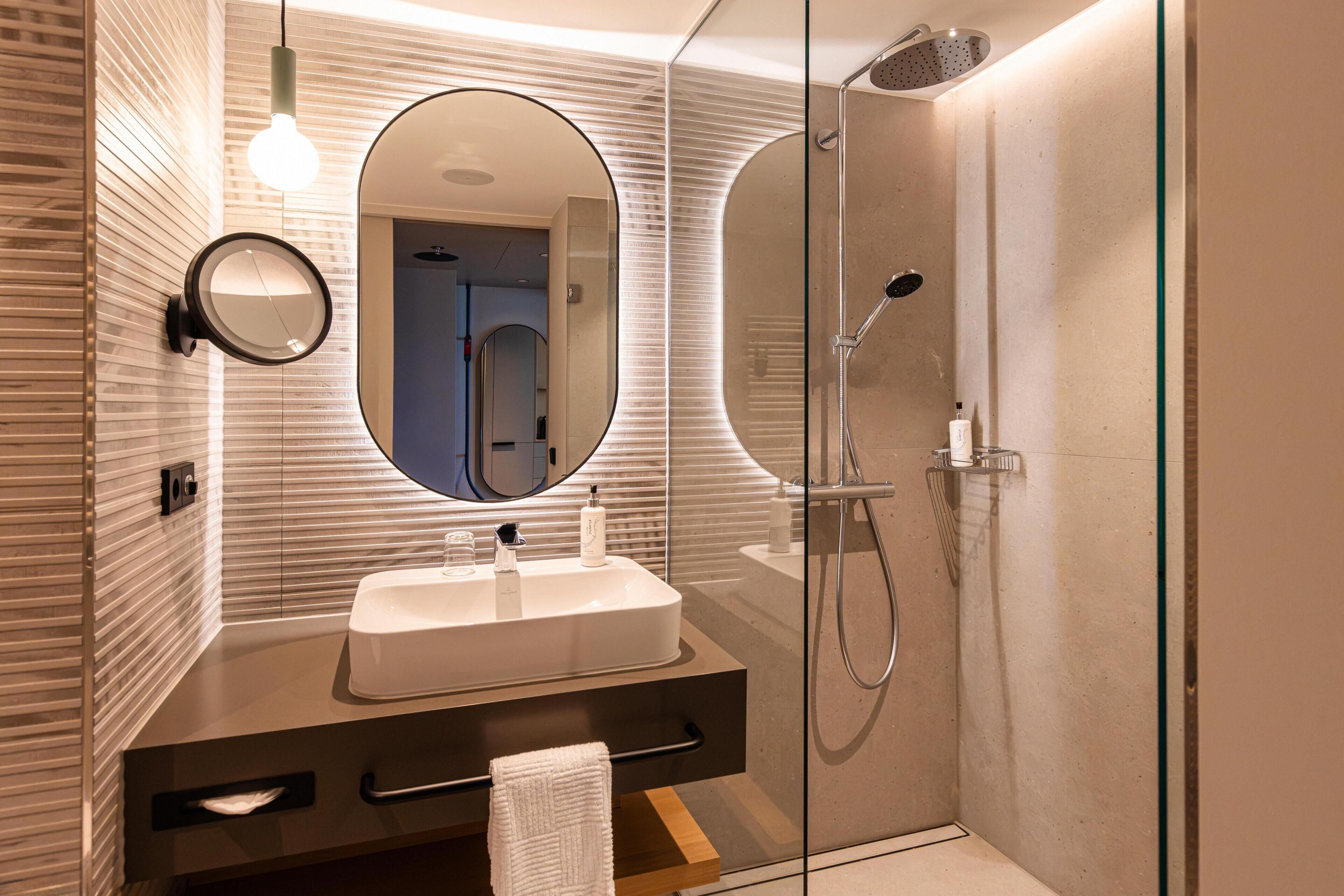 Een moderne badkamer met een grote spiegel, een wastafel en een douche.
