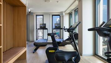 A modern gym with two treadmills, one elliptical, and a bench.