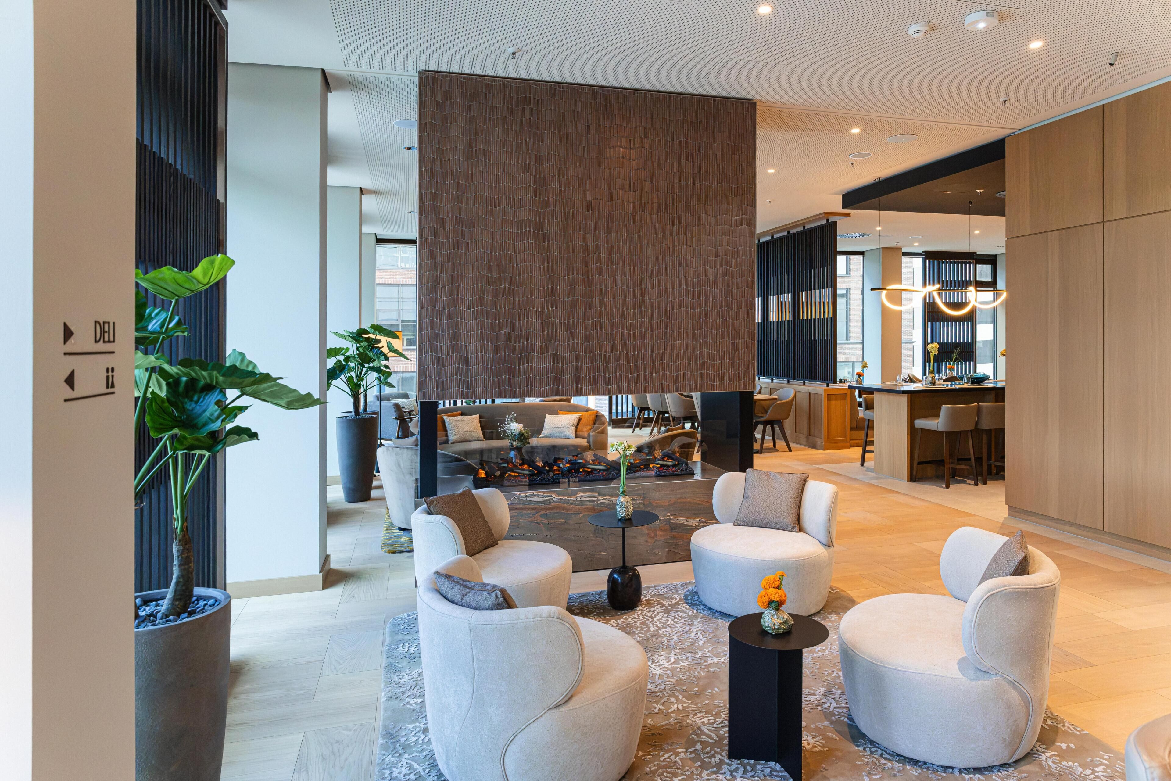A modern lobby with seating areas, a reception desk, and a large hanging light fixture.
