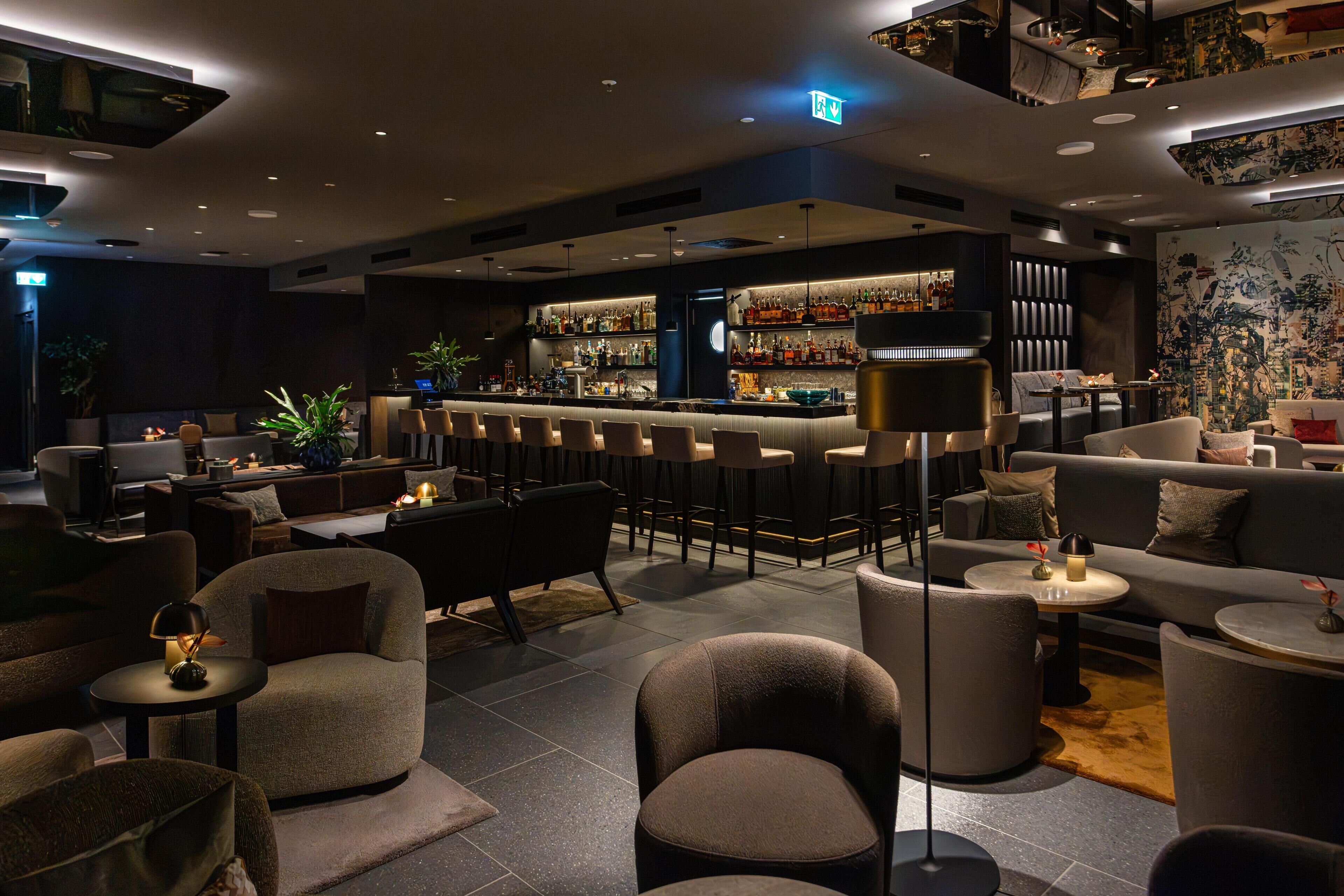 Un espace bar moderne comprenant un comptoir, des sièges et un mur décoratif.