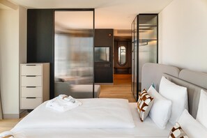 A modern hotel room with a bed, a dresser, a mirror, and a view of the hallway. - ATLANTIC Hotel Frankfurt - New opening (Frankfurt)