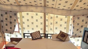 Ein Bett mit einer rot-weißen Tagesdecke, einem gemusterten Kopfkissen und einem roten Teppichboden.