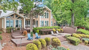 Una casa moderna con un patio in legno, arredi esterni e giardini curati.
