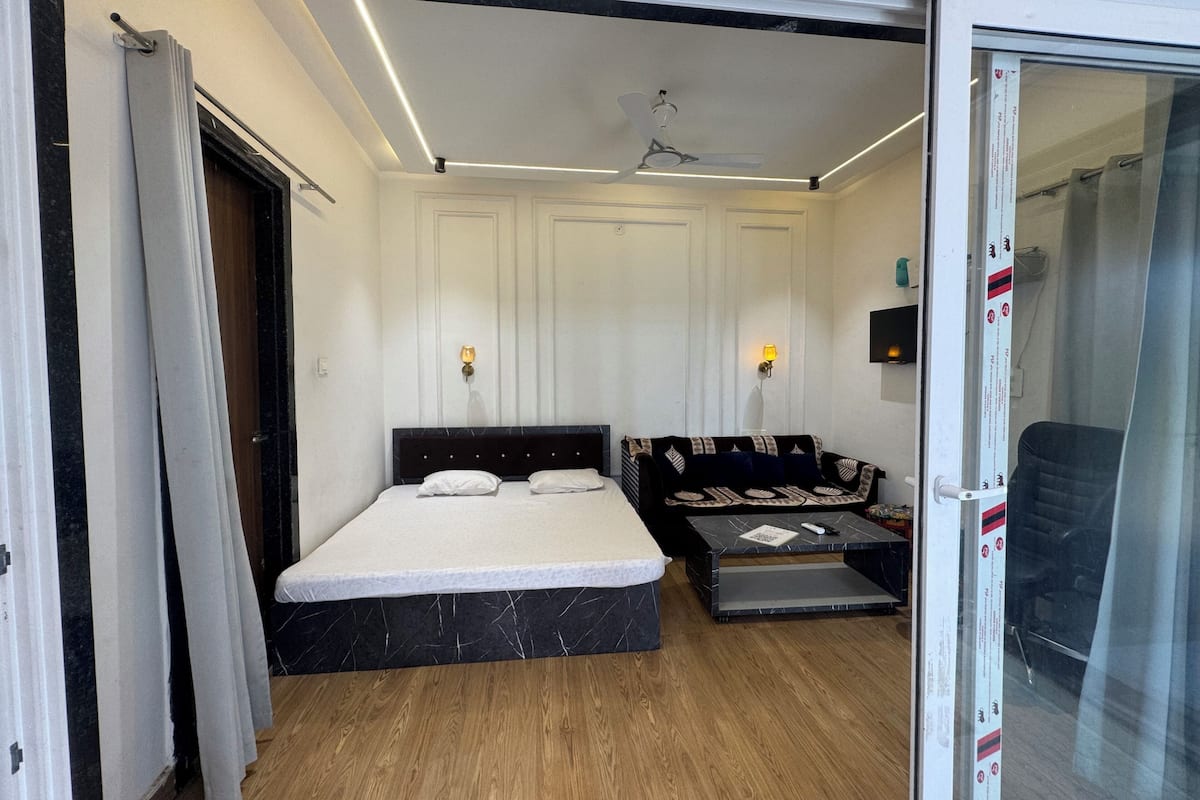 Una habitación de hotel con cama, sofá, una mesita y ventilador de techo.